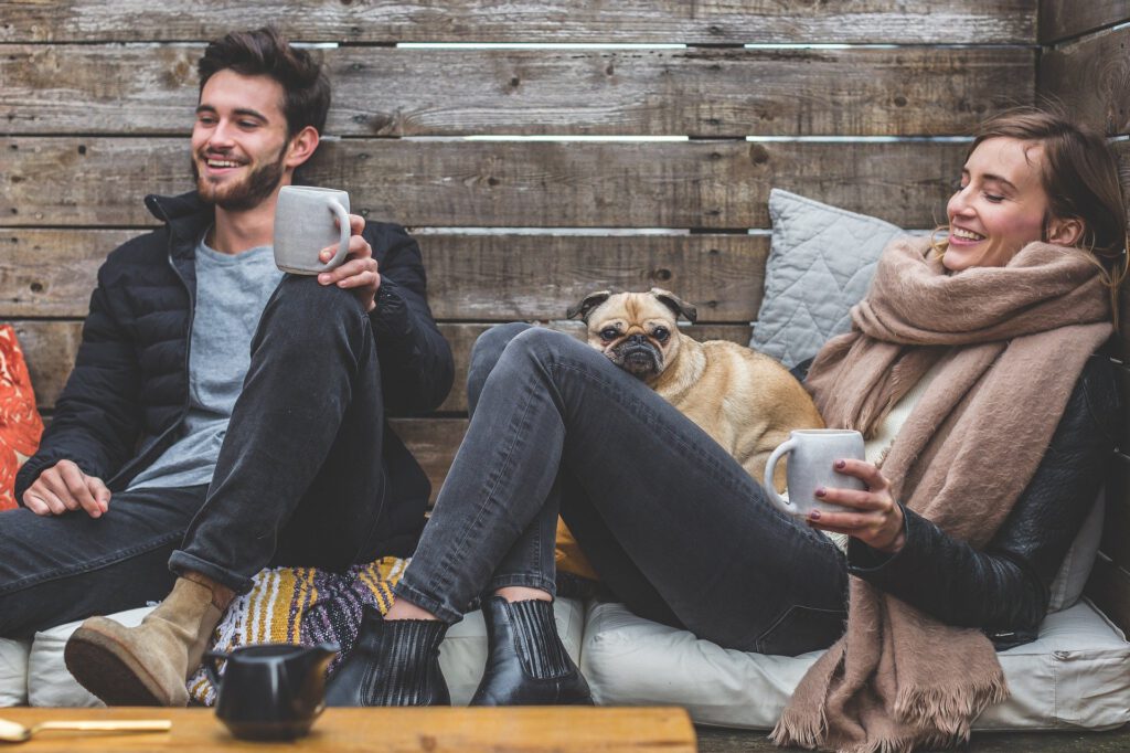 Relax - junge Menschen und ein Hund genießen Kaffee un Tee draußen